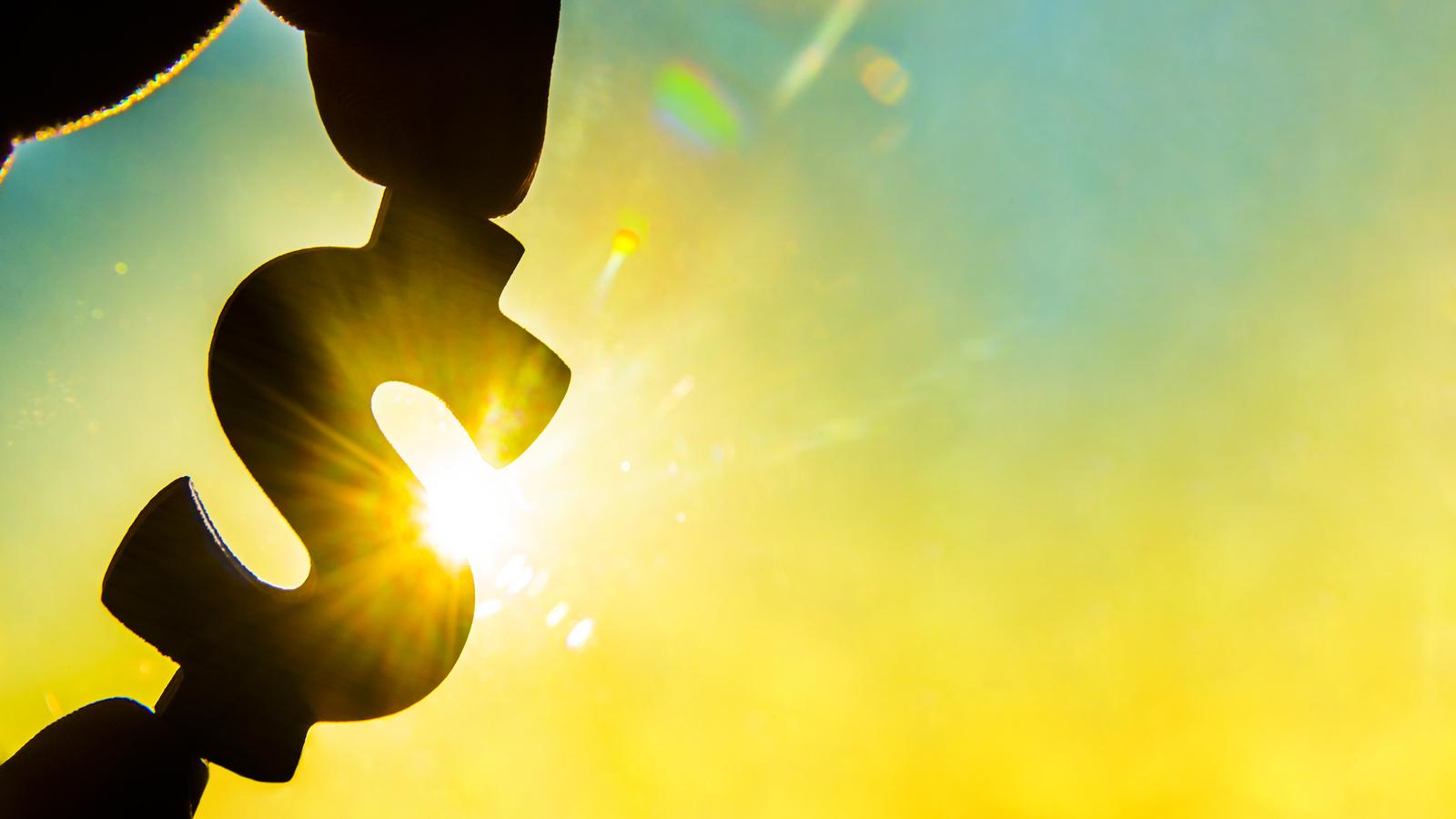 Dollar Sign Silhouette Against Sun